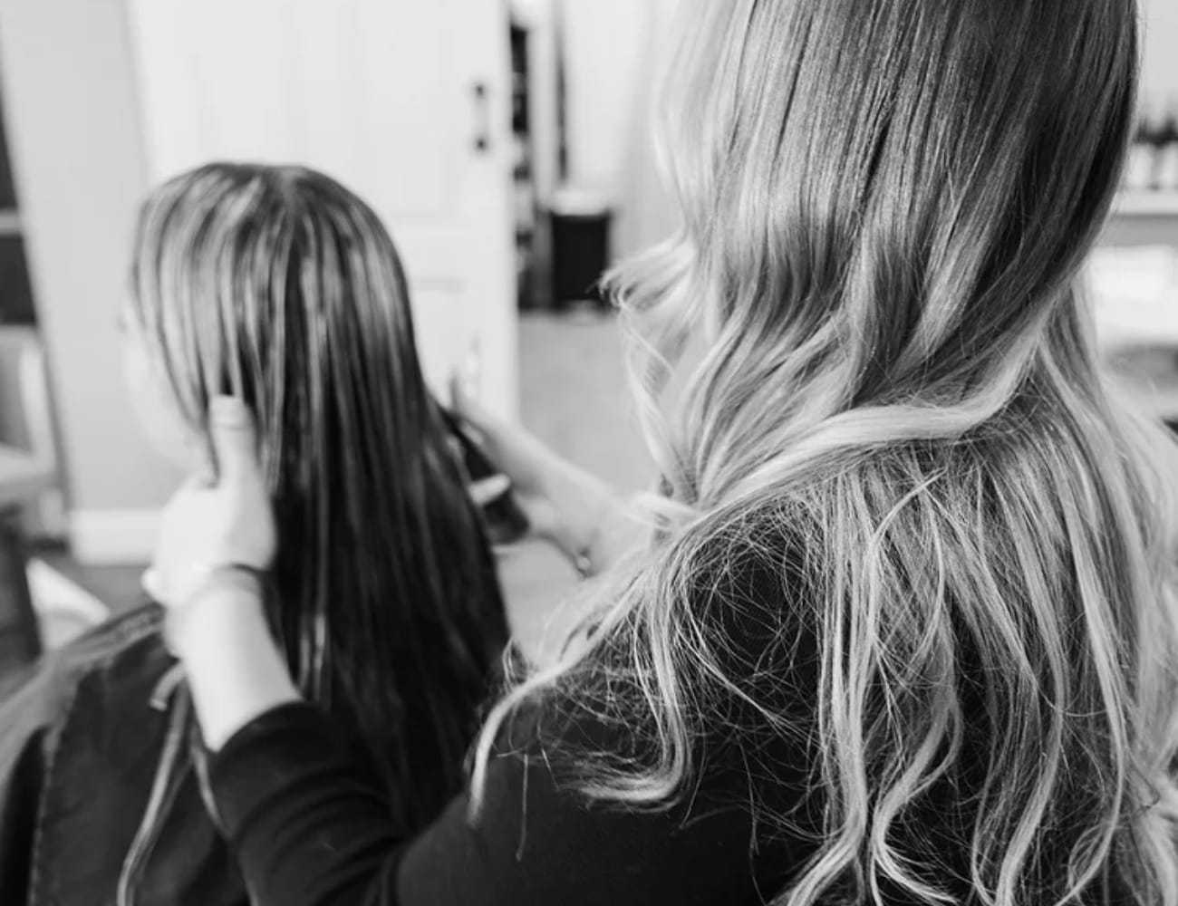 Hairdresser cutting a client's wet hair in a salon.