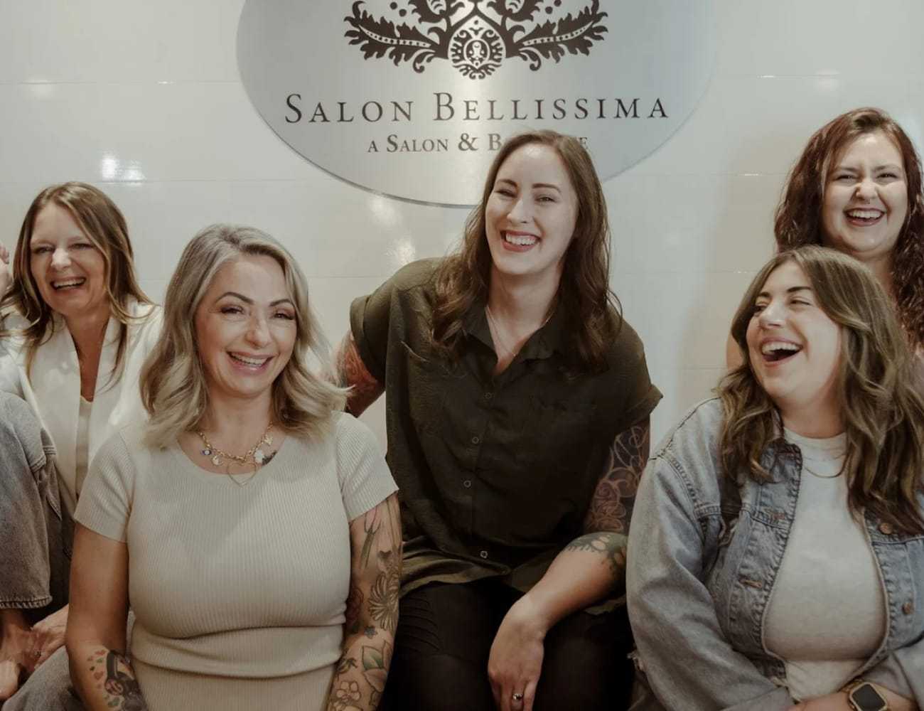 Group of smiling women sitting together at Salon Bellissima.